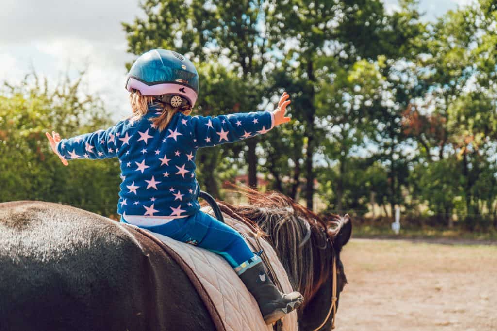 little girl with a helmet riding a horse in Colorado